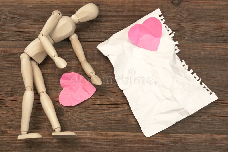 Wood Humane Figurine, Torn Blank Ð¡rumpled Paper Page And Two Broken Hearts On The Wood Background. Wood Humane Figurine, Torn Blank Ð¡rumpled Paper Page And Two Broken Hearts On The Wood Background